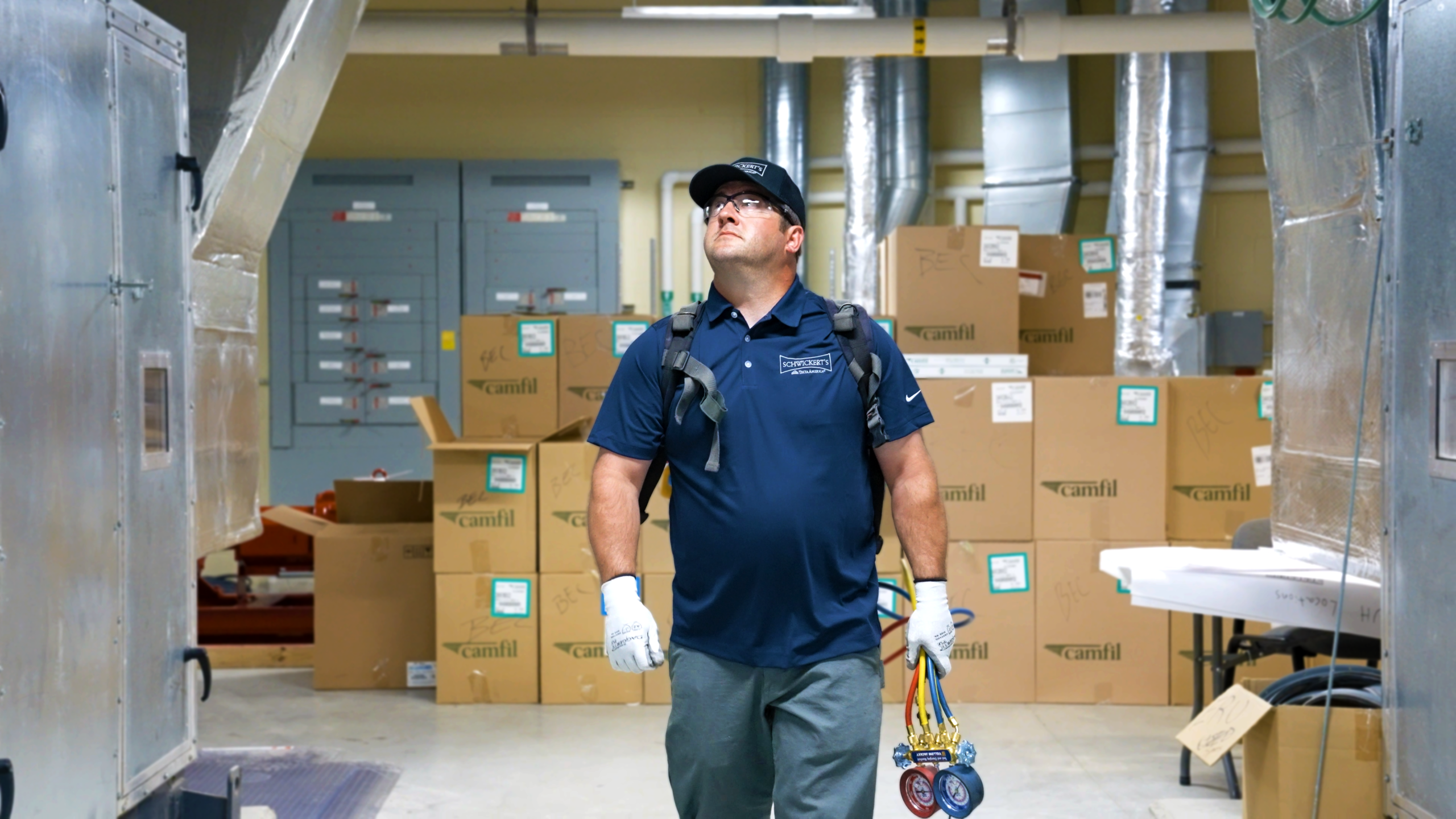 HVAC technician walking through middle aisle of mechanical room