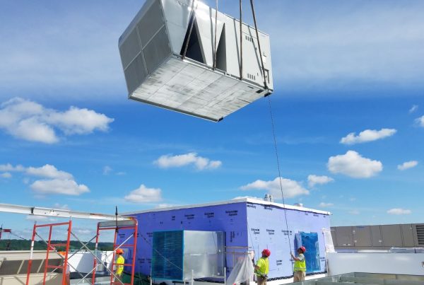 hvac unit being brought onto a rooftop via crane
