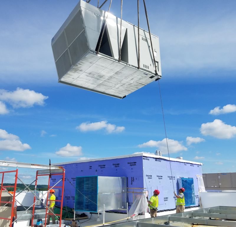 hvac unit being brought onto a rooftop via crane