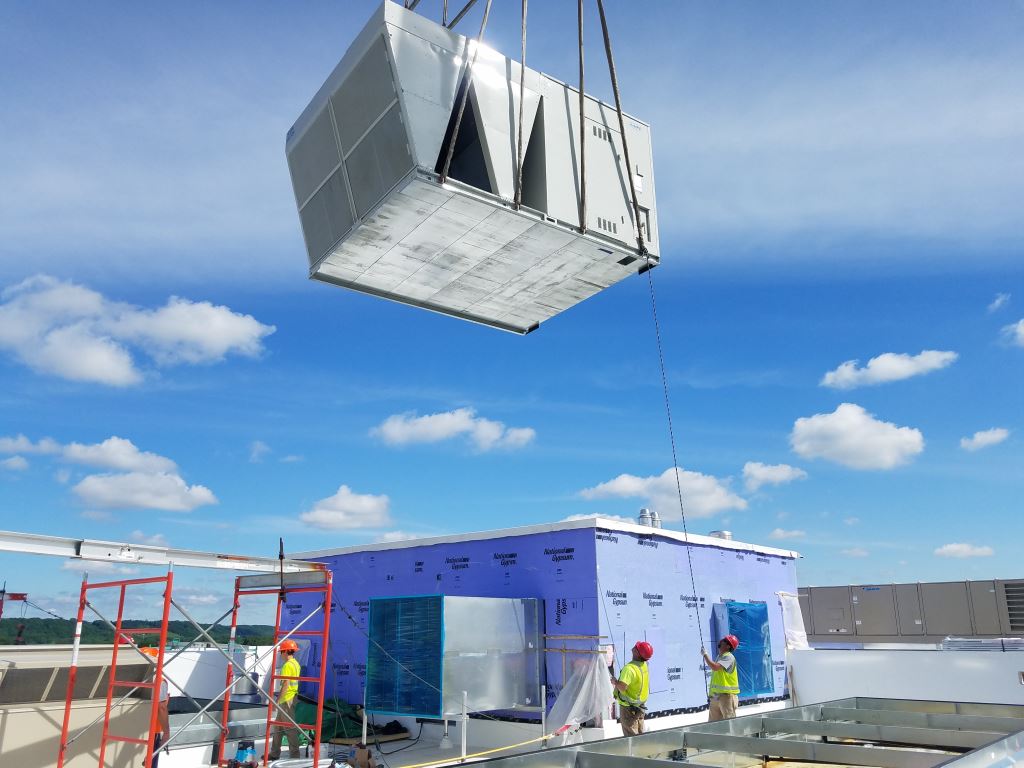 hvac unit being brought onto a rooftop via crane
